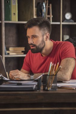 Açık laptop ile masanın arkasında oturan genç işadamı