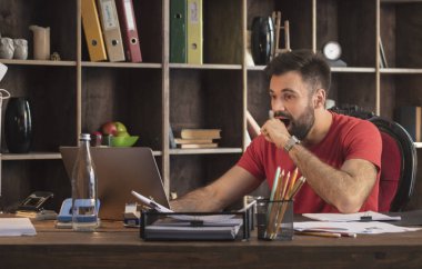 Studio dizüstü bilgisayar ile oturma ve şaşırtıcı haber tarafından şaşırtıcı genç işadamı