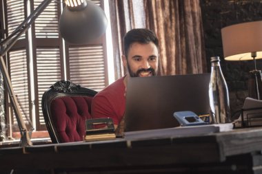 Sandalyede rahat karanlık ofisinde oturan ve dizüstü arıyorum genç iş adamı