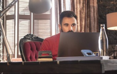 Dizüstü bilgisayar ile ofis koltuğu oturan genç işadamı