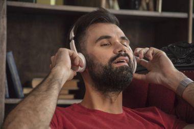 Büyük bir zevk ile rahatlatıcı müzik dinlerken kulaklık sakallı genç adam