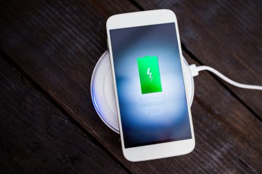 Beyaz smartphone şarj bir yastık üzerinde şarj.