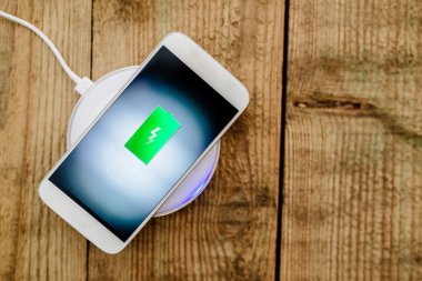 Beyaz smartphone şarj bir yastık üzerinde şarj.