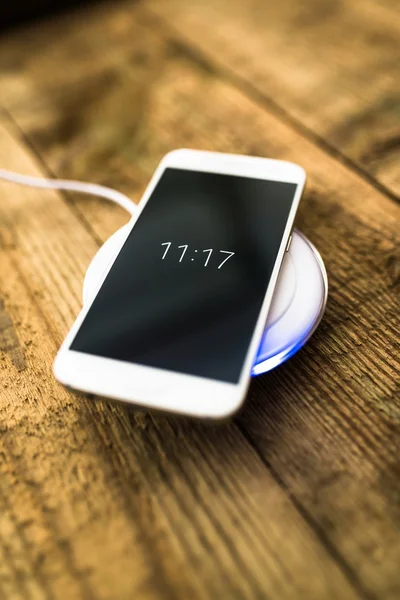 White smartphone charging on a charging pad.