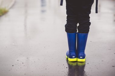 Çocuk kauçuk Wellington ıslak patika üzerinde ayakta.