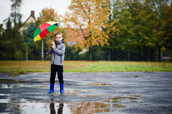 Niño triste caminando en hule wellingtons en sendero mojado . — Foto de Stock