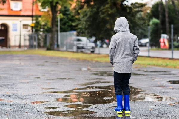 Menino de borracha botas de chuva azul andando na chuva — Fotografia de Stock