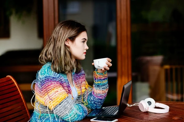 コーヒーを飲みながらカラフルなウールのセーターの若い女性 — ストック写真