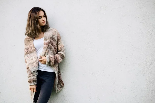 Woman in woolen sweater posing against a white wall — Stock Photo, Image