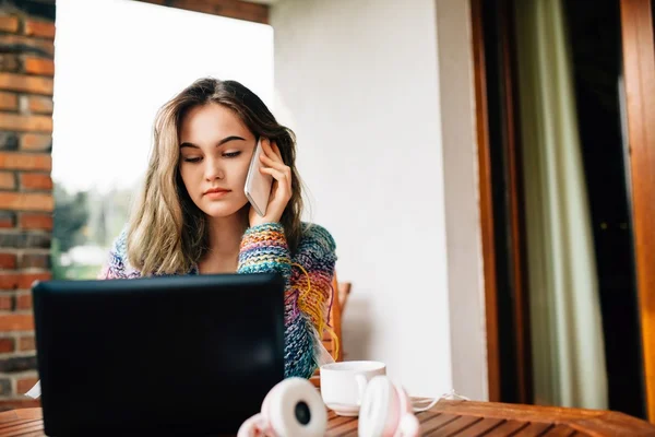 Mujer utiliza un teléfono inteligente y ordenador portátil —  Fotos de Stock