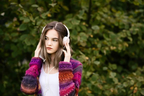 Mujer en suéter de lana escuchando música en el parque —  Fotos de Stock