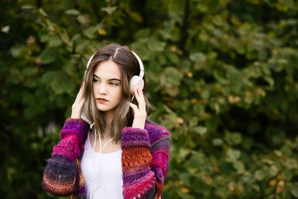 Femme en chandail de laine écoutant de la musique dans le parc — Photo