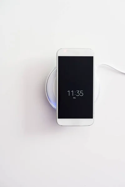 Smartphone branco carregado pelo carregador sem fio — Fotografia de Stock