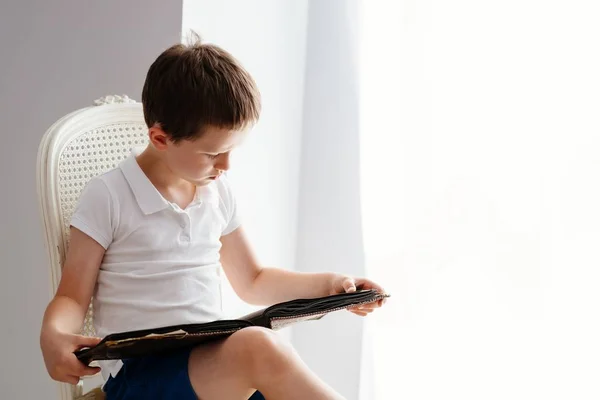 Pequeño niño de 7 años hojeando viejo álbum de fotos . — Foto de Stock