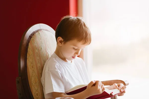 Pequeño niño de 7 años leyendo un libro . — Foto de Stock