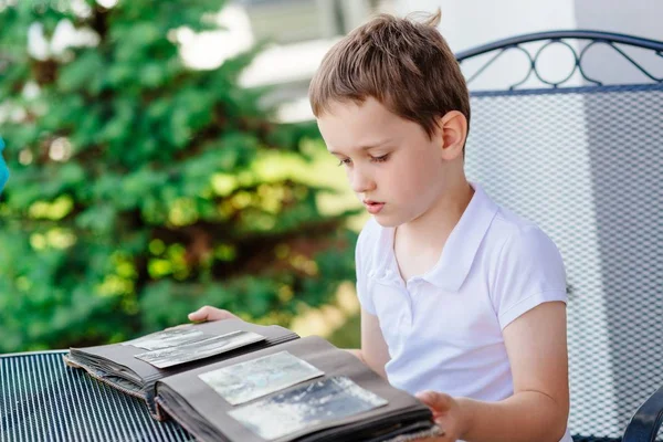 Little 7 years old boy browsing old photo album. — Stock Photo, Image