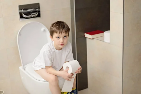 Little 7 years old boy sitting on toilet. — Stock Photo, Image