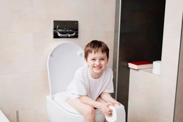 Little 7 years old boy sitting on toilet. — Stock Photo, Image