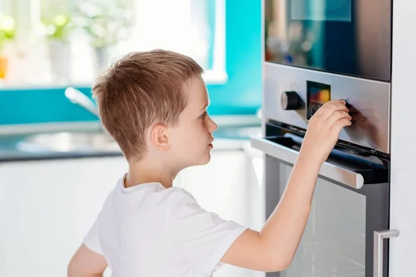 Child regulating temperature of the oven . — Stock Photo, Image