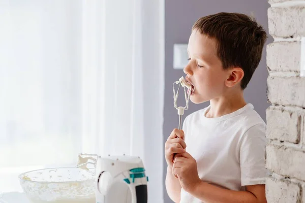 Barn provsmakning bakverk från mixer omrörare — Stockfoto