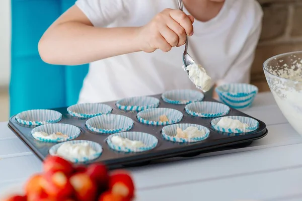 Kind füllt Cupcakes mit Teigzutaten — Stockfoto