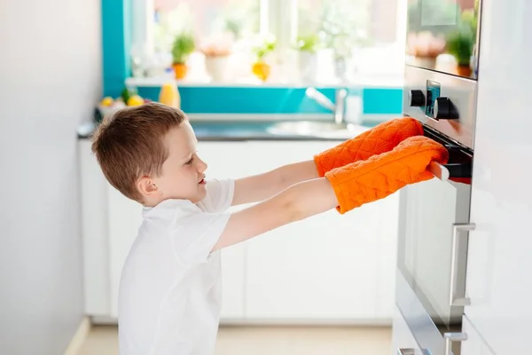 Copilul deschide cuptorul în bucătărie . — Fotografie, imagine de stoc