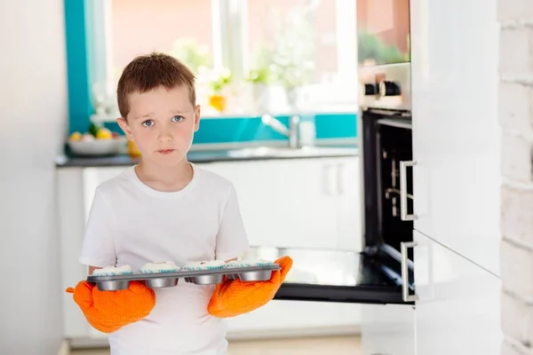 Niño sosteniendo bandeja para hornear con cupcakes —  Fotos de Stock