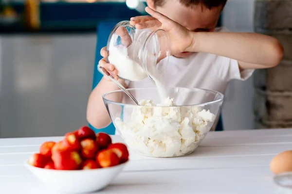 Niño añadiendo azúcar al queso blanco en un tazón para pastel de queso . — Foto de Stock