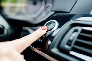 Kadın arabanın motoru start-stop düğmesi ile başlar.