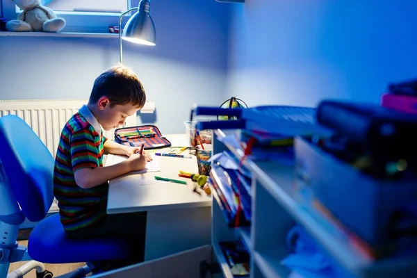 Ребенок делает домашнее задание в свете лампы — стоковое фото