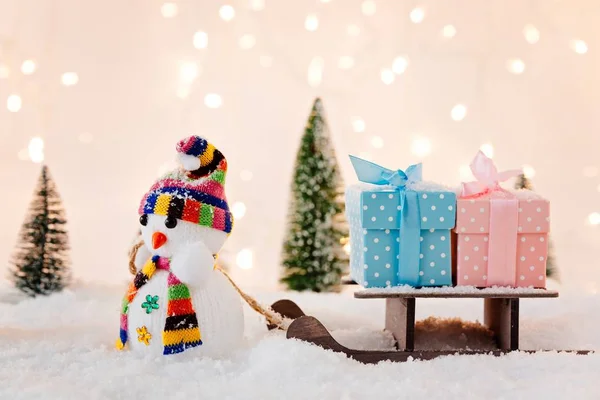 Juguete muñeco de nieve tirando pequeño trineo de madera con regalos de Navidad . — Foto de Stock