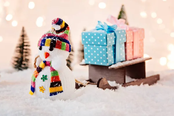 Zabawka bałwana ciągnąc małe drewniane sanie z prezenty świąteczne. — Zdjęcie stockowe
