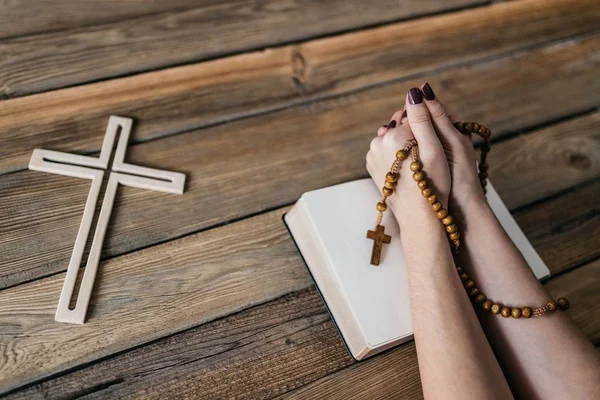 Mani di donne con rosario in legno e Sacra Bibbia — Foto Stock