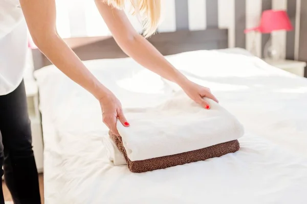 Giovane cameriera dell'hotel mettendo asciugamani freschi su un letto — Foto Stock