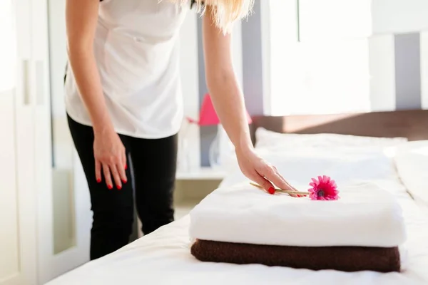 Jovem empregada do hotel colocando flor em toalhas frescas — Fotografia de Stock