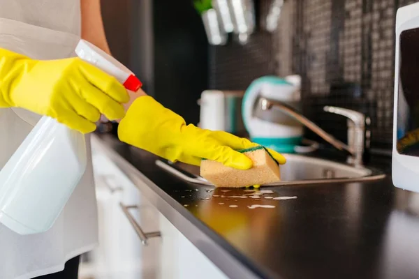 Donna che pulisce armadi cucina con spugna e detergente spray — Foto Stock