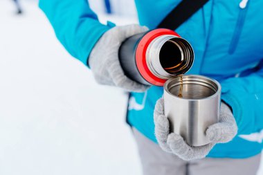 Kadın mavi ceketli bir termos sıcak çay dökme