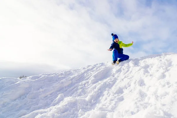 Joyeux enfant glissant de petite colline enneigée — Photo