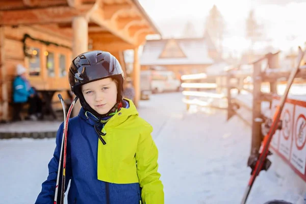 Enfant avec un casque de ski noir tenant ses skis — Photo