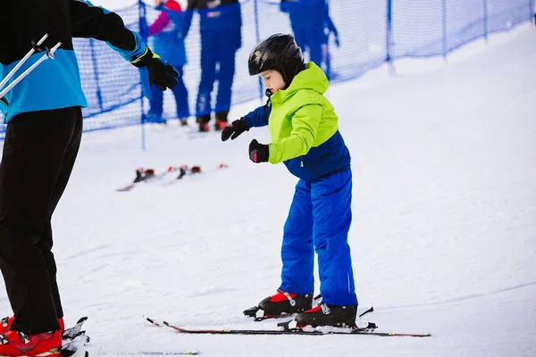 Παιδί με ένα μαύρο κράνος μαθαίνει να κάνει σκι με εκπαιδευτή — Φωτογραφία Αρχείου