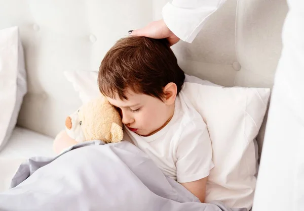 Больной ребенок обнимает плюшевого медведя — стоковое фото