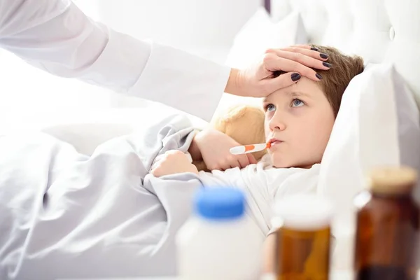 Niño enfermo con temperatura en la cama . — Foto de Stock