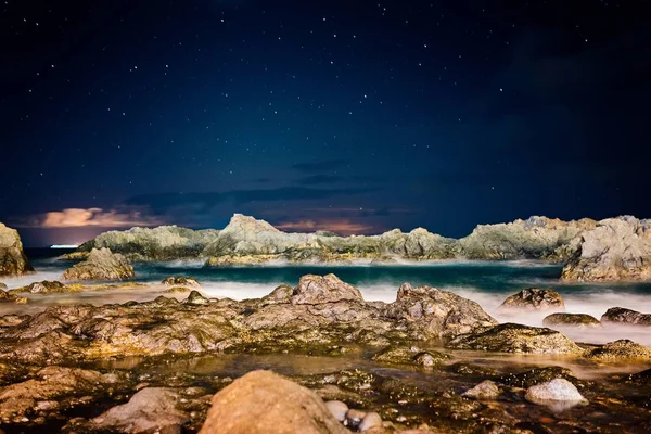 Hermosa vista nocturna sobre el océano y las rocas . — Foto de Stock