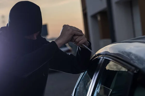 Auto thief in black balaclava trying to break into car — Stock Photo, Image