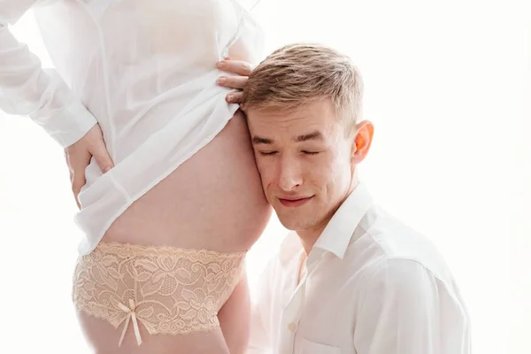 Муж слушает животик беременной жены. — стоковое фото