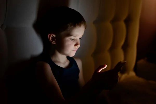 7 år gamla barn pojke med smartphone på natten — Stockfoto