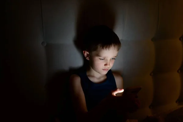 Enfant garçon de 7 ans utilisant un smartphone la nuit — Photo