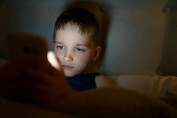 7 éves gyermek fiú használ smartphone éjjel — Stock Fotó