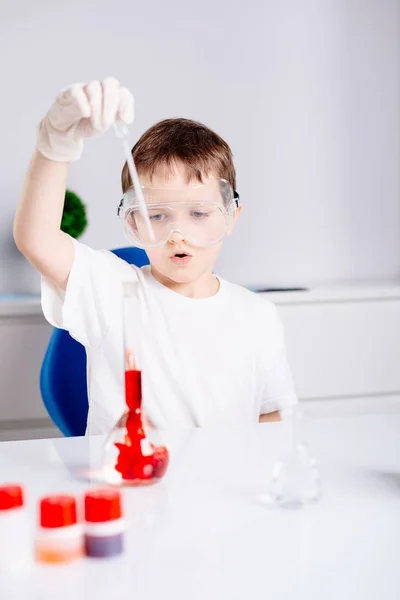 Poika sekoittamalla värillisiä nesteitä koeputkissa — kuvapankkivalokuva