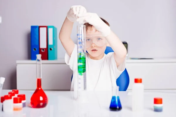 Poika sekoittamalla värillisiä nesteitä koeputkissa — kuvapankkivalokuva